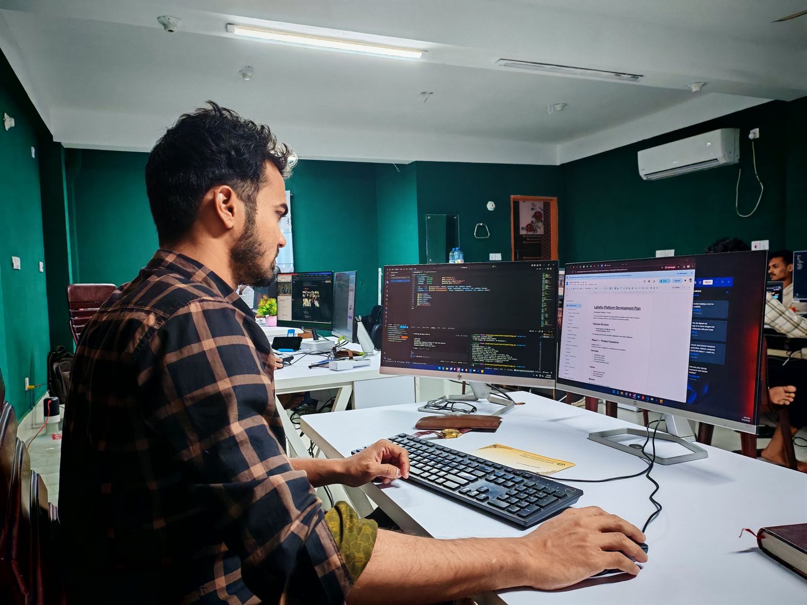 A software engineer working at a multi-screen development workstation